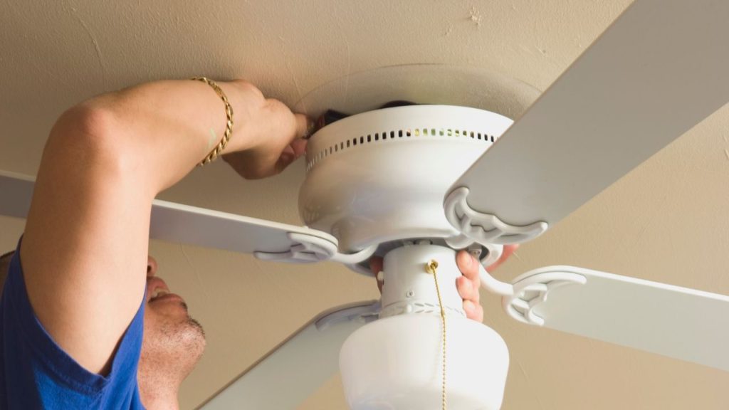 Man attaching the new ceiling fan fixture on the ceiling
