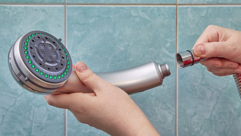 Woman installing a showerhead to the shower hose