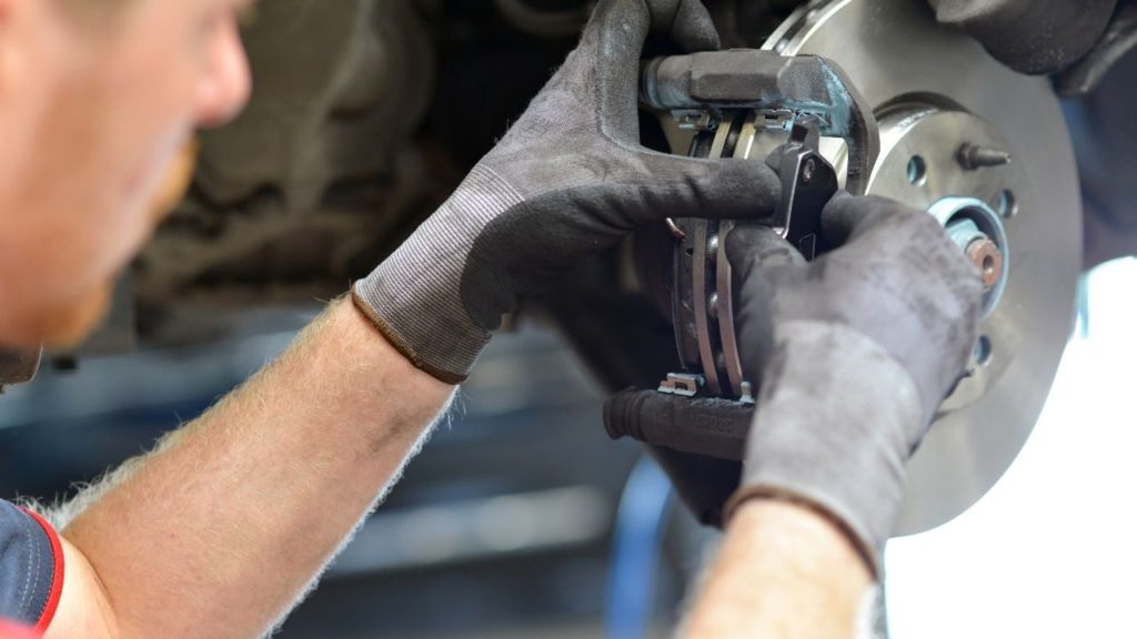 A person installing brand-new car brake pads for car maintenance