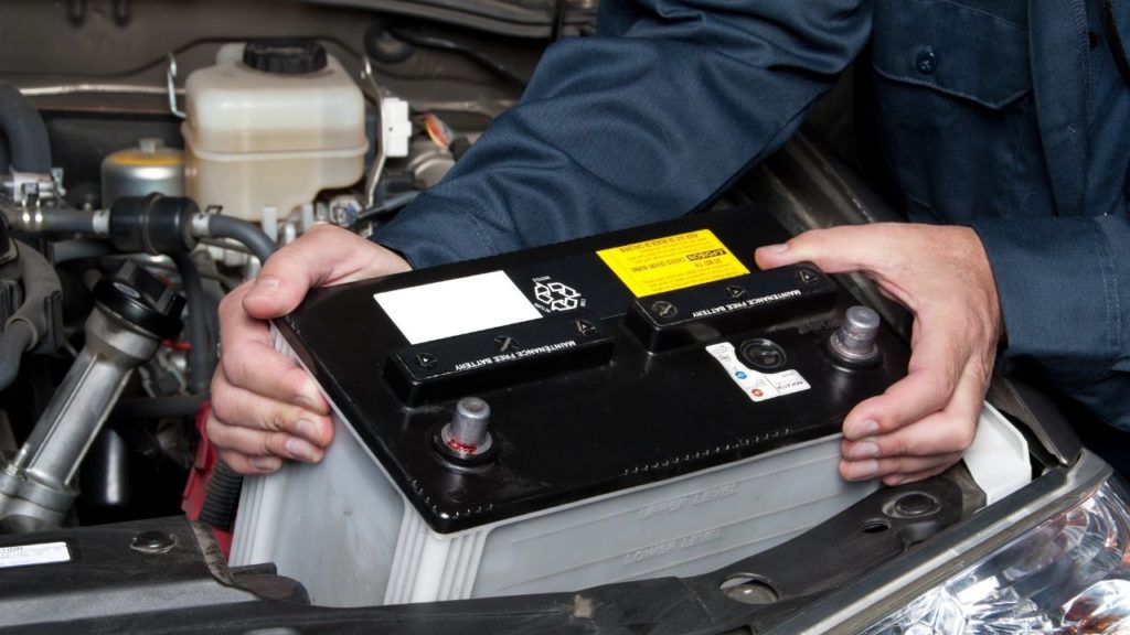 A person removing a car battery for car maintenance checklist