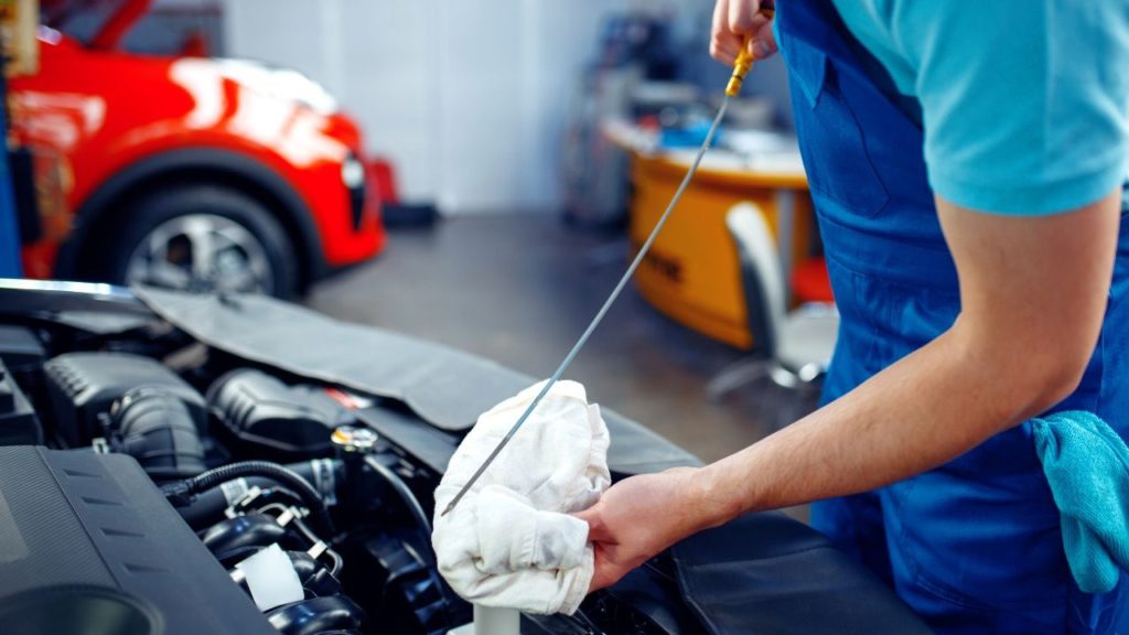 A person checking the engine oil level by using a dip stick