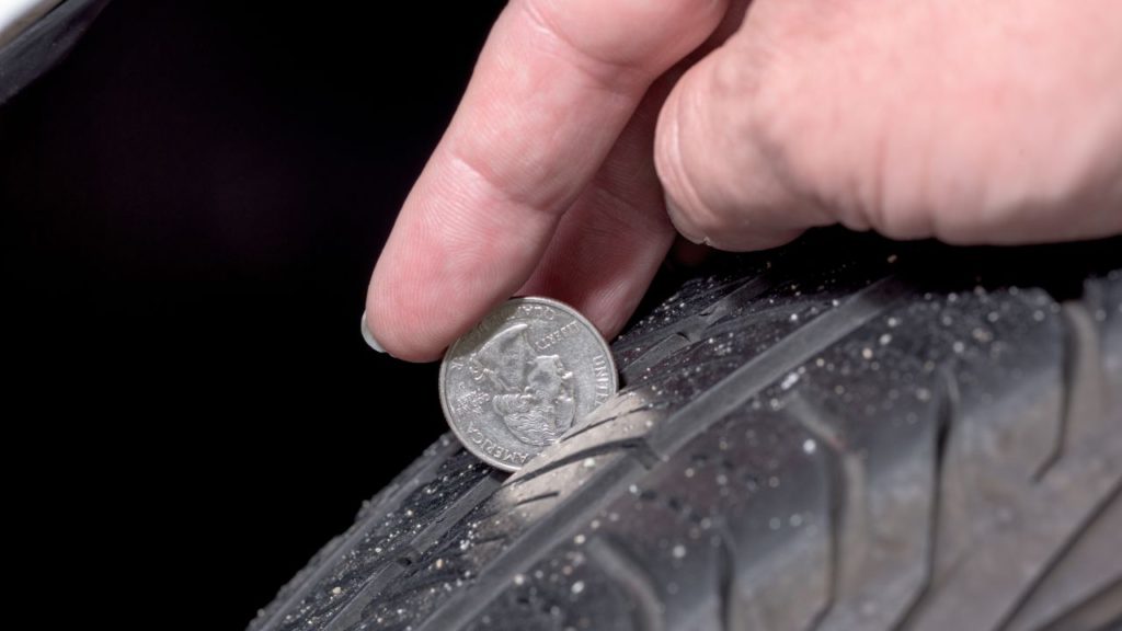A person using a penny to check how often to replace tires.