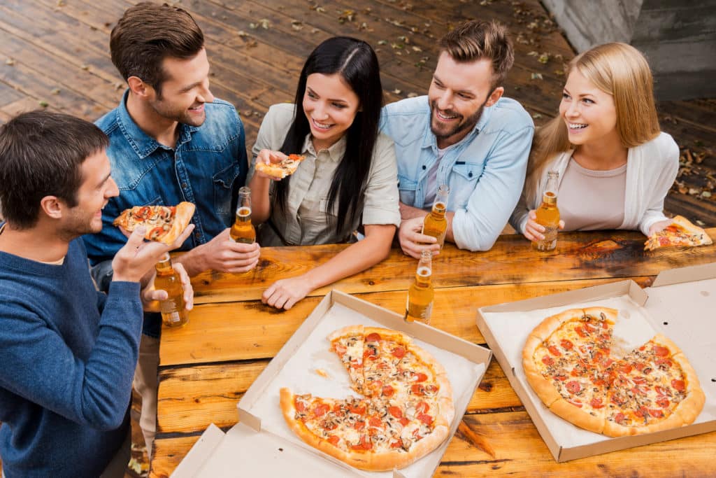 Carefree Time With Friends. Top View Of Five Cheerful Peopleholding Bottles With Beer And Eating Pizza While Standing Outdoors