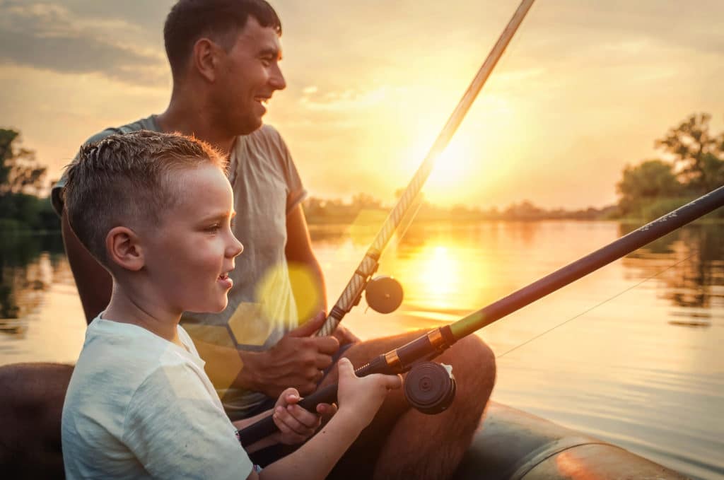 Happy,father,and,son,together,fishing,from,a,boat,at