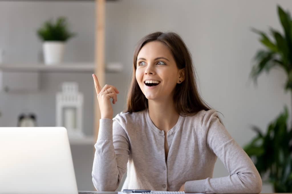 Young,happy,woman,sitting,at,desk,near,laptop,gesturing,with