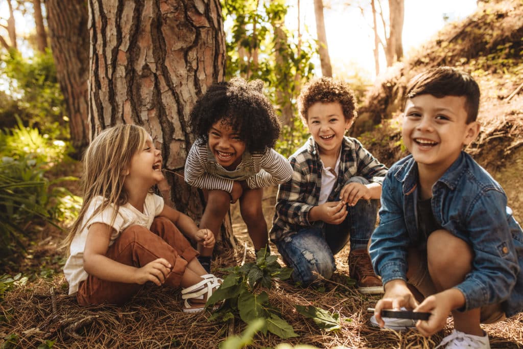 Group,of,cute,kids,sitting,together,in,forest,and,looking