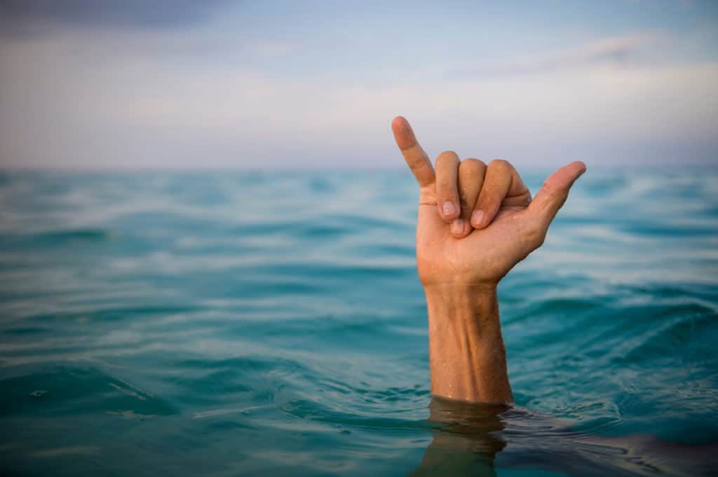 Hand,of,surfer,making,shaka,(hang,loose),sign,in,tropical