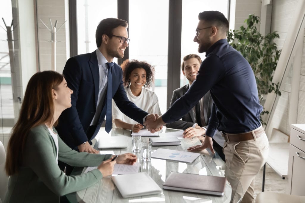 Smiling,multiethnic,male,business,partners,shake,hands,close,deal,make