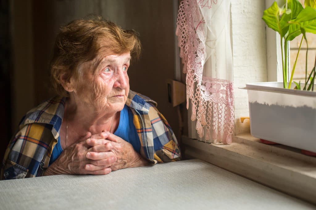 Old,lonely,woman,sitting,near,the,window,in,his,house.