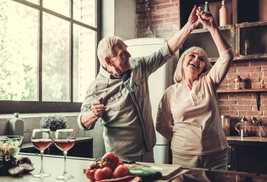 Beautiful,senior,couple,is,dancing,and,smiling,while,cooking,together