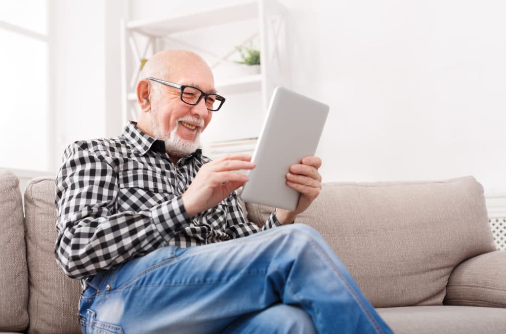 Smiling,senior,man,reading,news,on,digital,tablet.,cheerful,excited