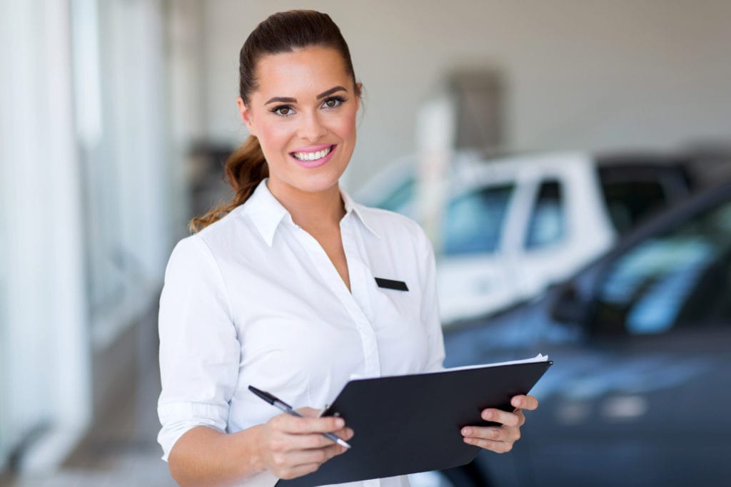 young car saleswoman holding clipboard