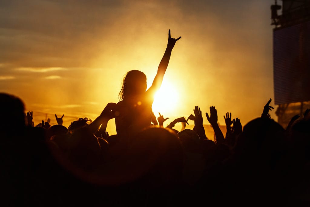 Young girl enjoys a rock concert, Silhouette on sunset