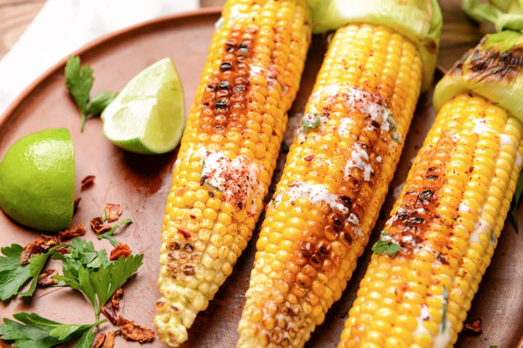 Plate With Tasty Grilled Corn Cobs On Table