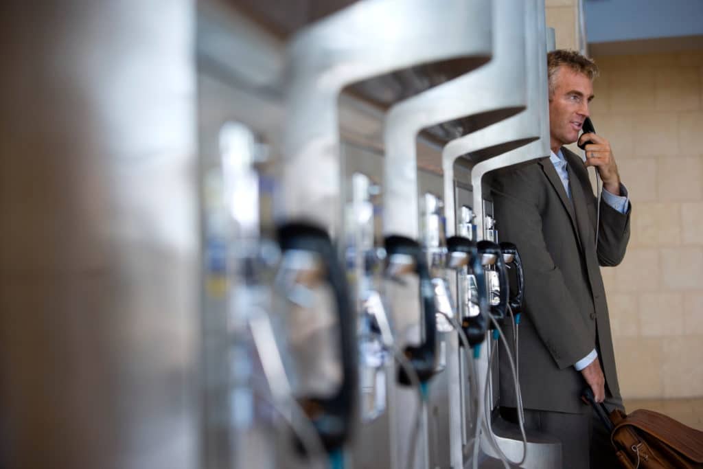 Senior Businessman Standing Besides A Public Payphone And Talking Over