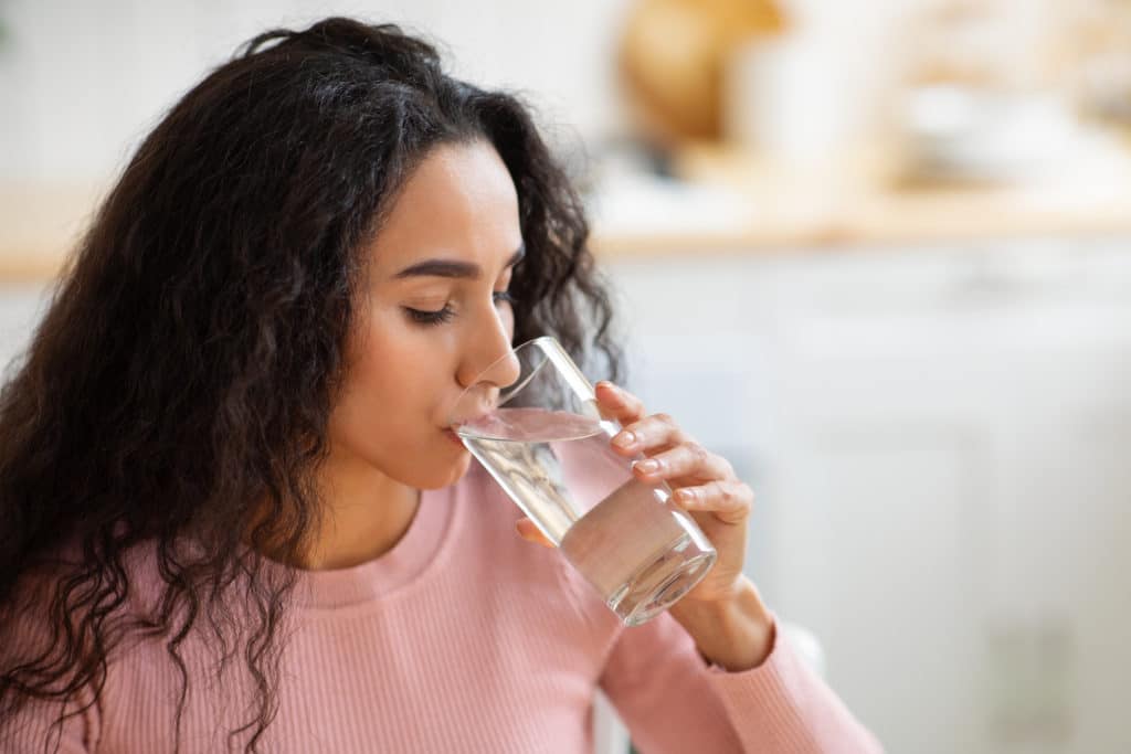 Healthy Liquid. Beautiful Brunette Woman Drinking Mineral Water From Glass