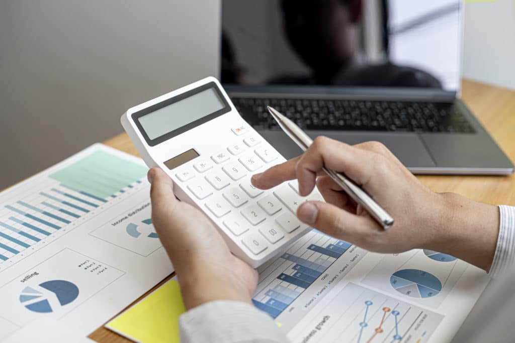 Businessman Using A Calculator To Calculate Numbers On A Company's