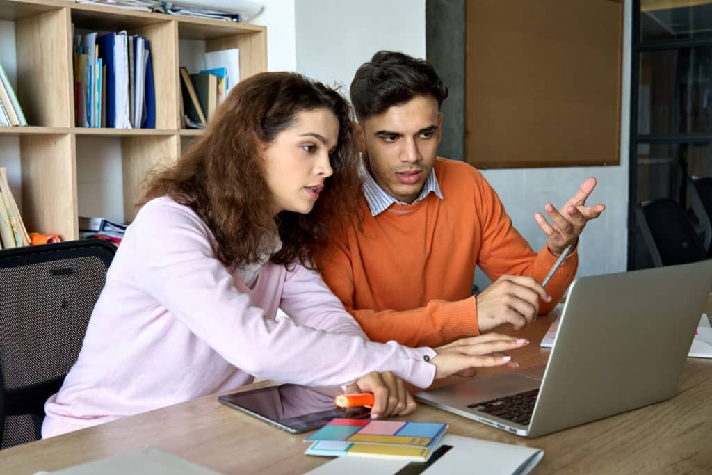 Two Young Male And Female Students Explaining Class Work Using