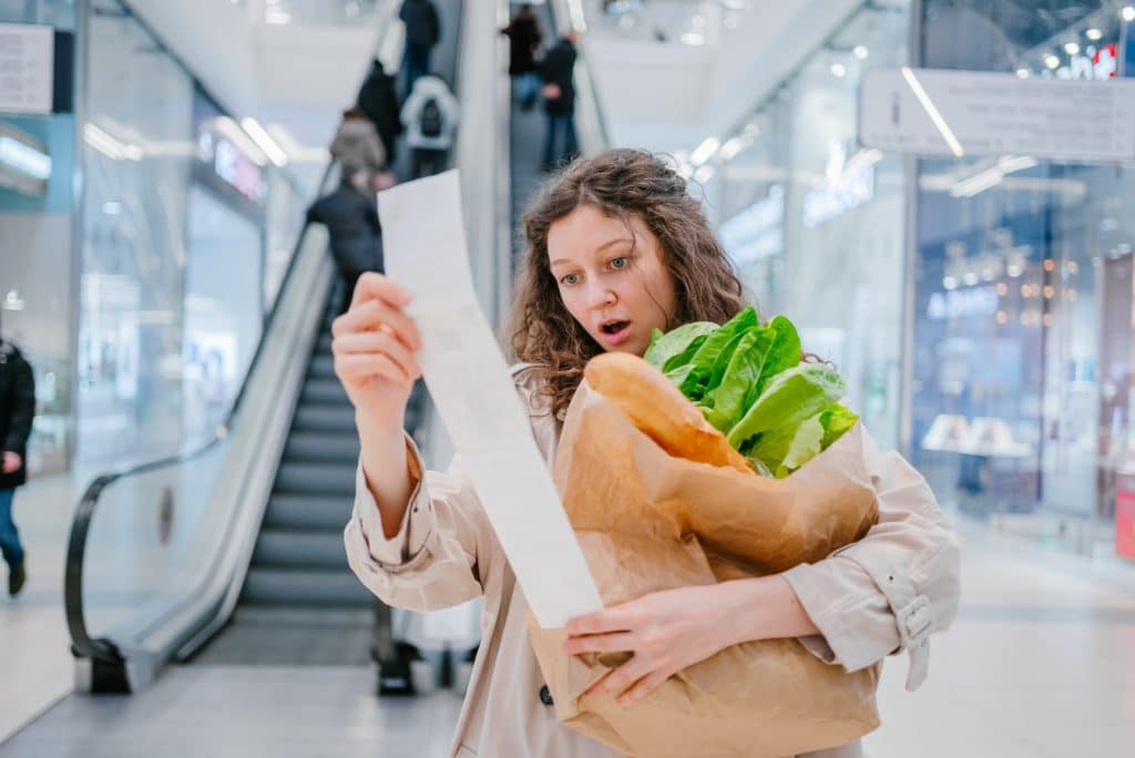 A Woman In Shock Looks Into A Paper Check From