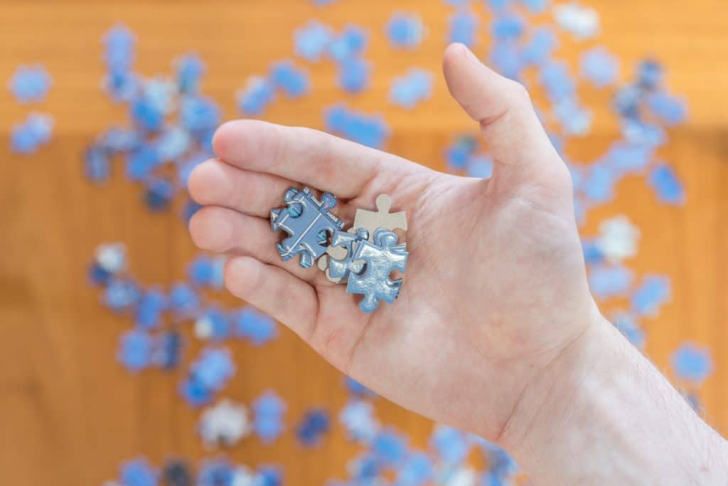 Hand Close Up Holding Blue Jigsaw Puzzle Pieces. Person Trying