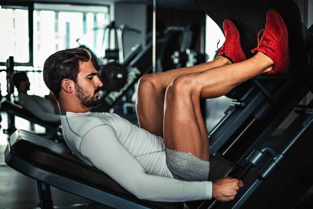 Man Focused On Training Legs On The Machine In The