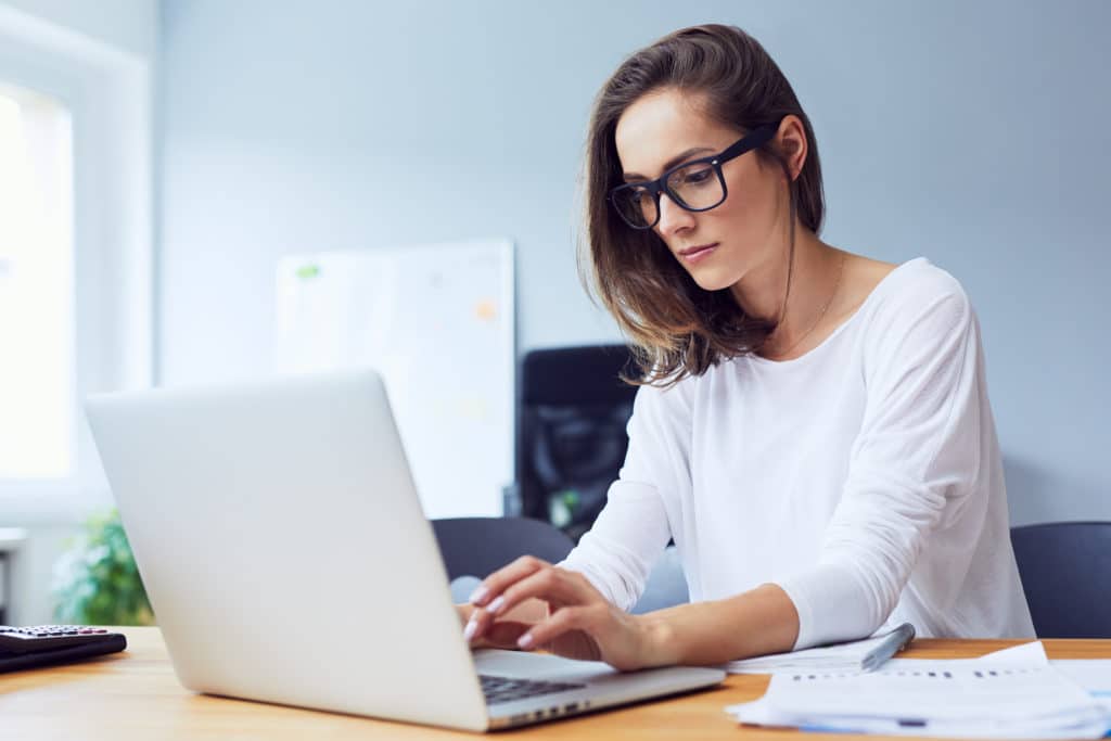 Concentrated Young Beautiful Businesswoman Working On Laptop In Bright Modern