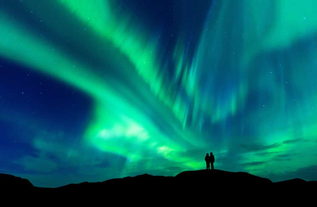 Aurora Borealis With Silhouette Love Romantic Couple On The Mountain.honeymoon