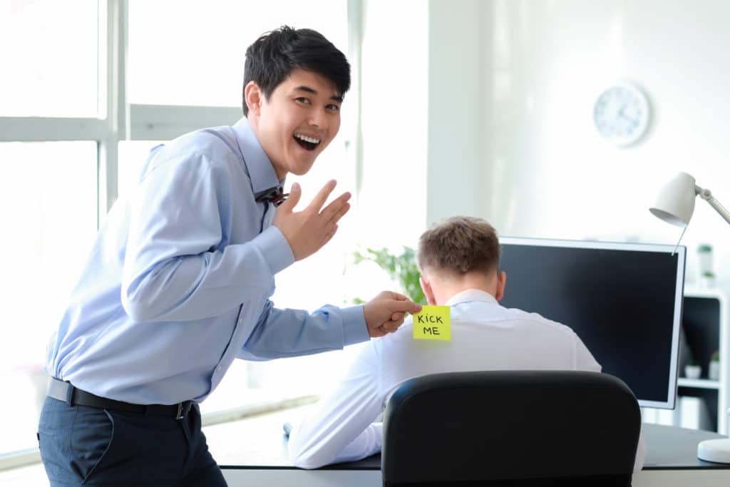 Asian Man Playing A Prank On His Colleague In Office.