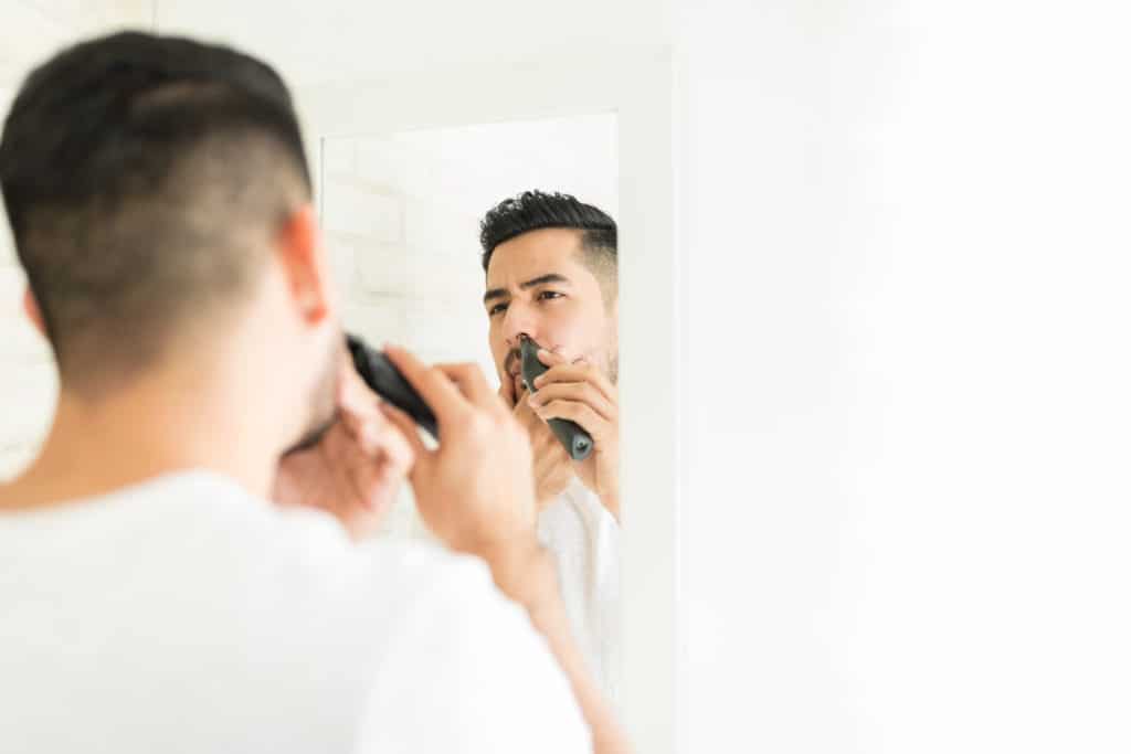 Reflection Of Man Cutting His Nasal Hair With Trimmer In