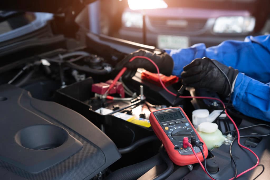 Asian Technician Measure Voltage Of Battery In The Car At