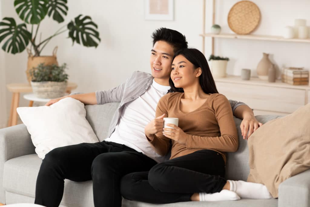 Smiling Asian Couple Relaxing And Watching Tv At Home Having