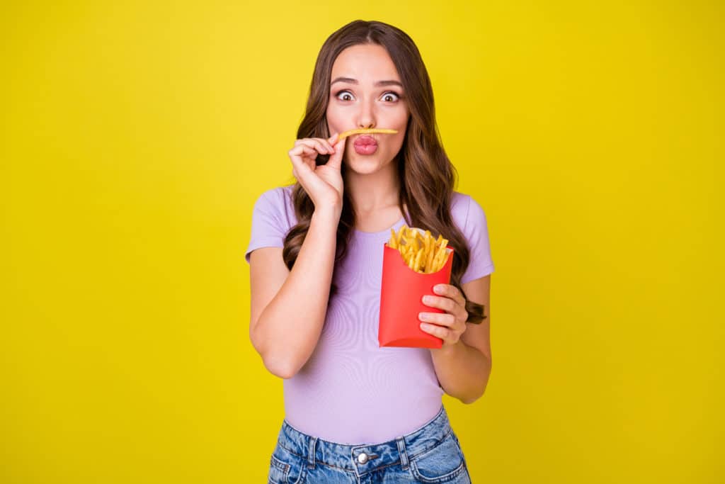 Portrait Of Attractive Funky Cheerful Wavy Haired Girl Eating French Fries