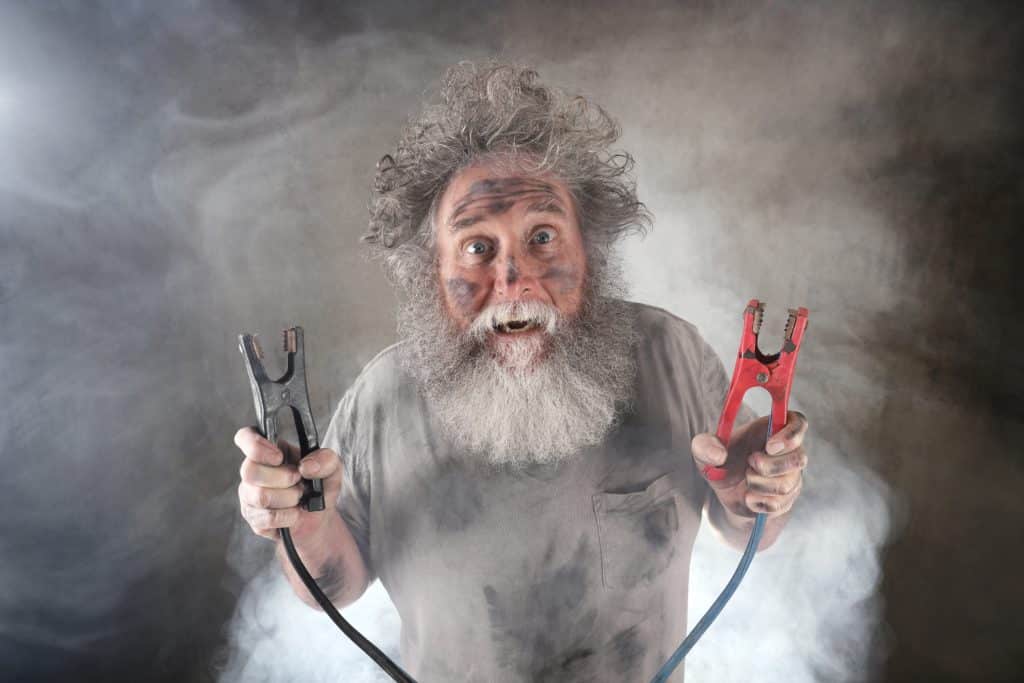 Suprised Old Man With Beard Holding Jumper Cables Surrounded By