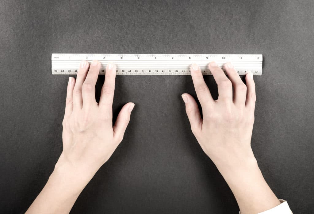 Two Woman Hands With Silver Ruler On Black Background. Woman