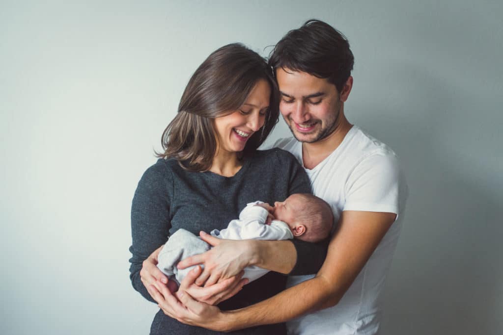 Woman And Man Holding A Newborn. Mom Dad And Baby.