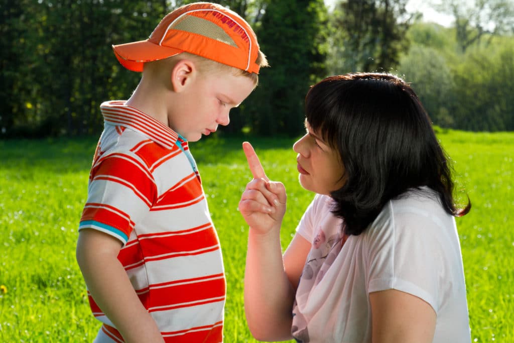 Mother Scolding Her Son With Pointed Finger In Park