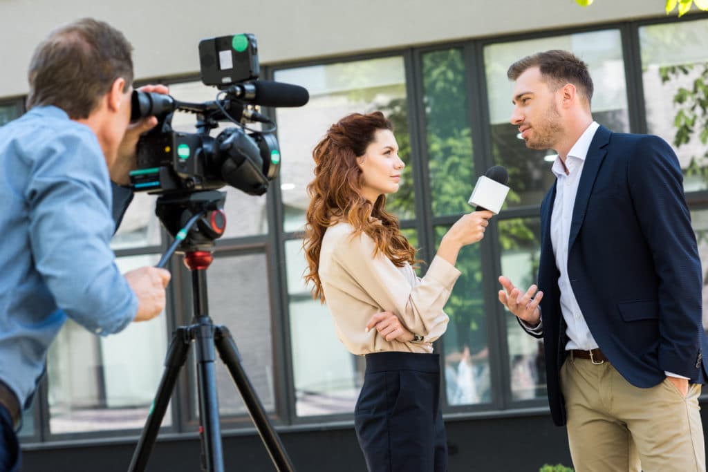 Professional Cameraman And Journalist Interviewing Businessman Near Office Building