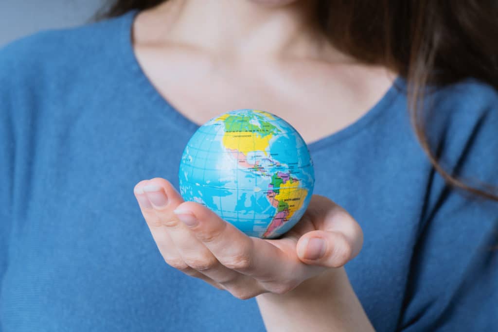 Young Unrecognizable Woman Holding World Globe In Her Hands 