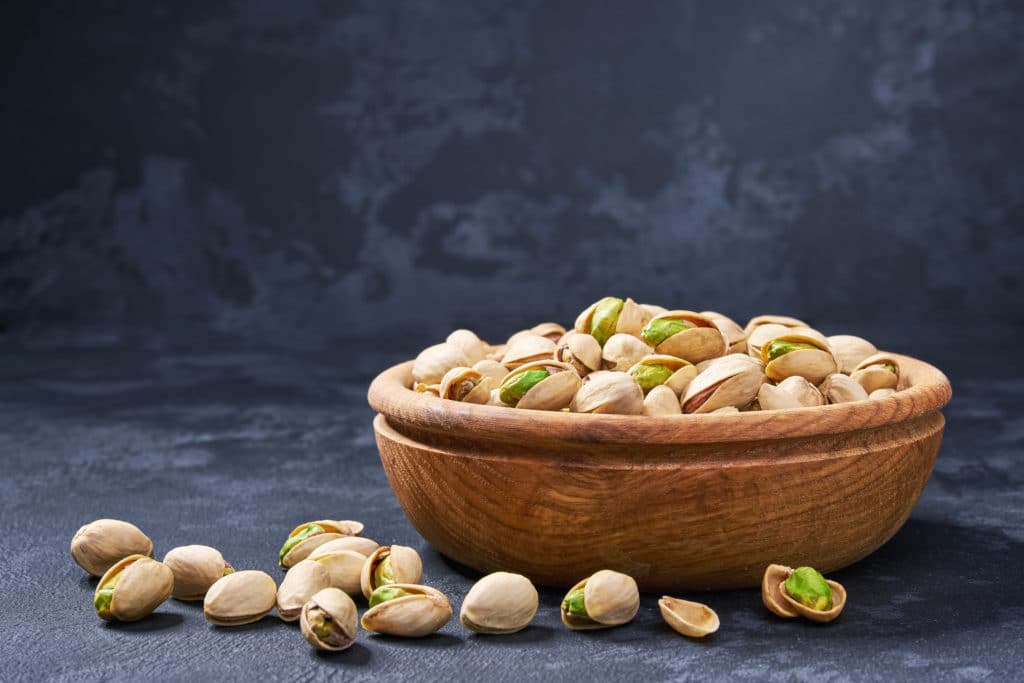Pistachios In Wooden Bowl On Black Background. Organic Pistachios Healthy