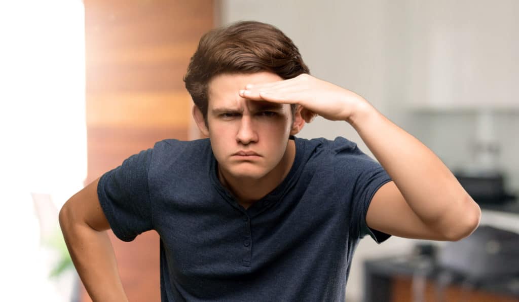 Teenager Man Looking Far Away With Hand To Look Something