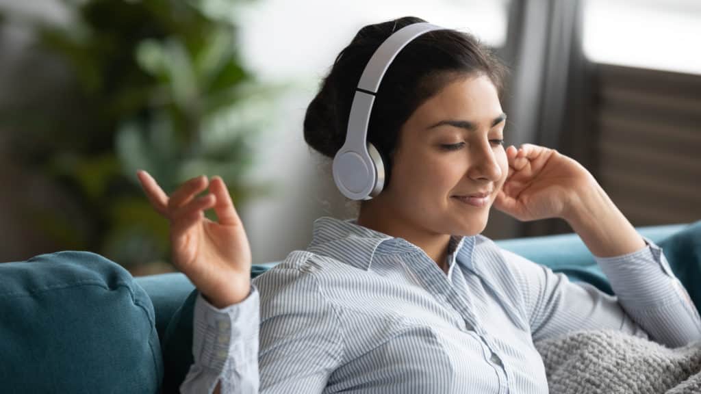 Happy Carefree Indian Ethnic Girl Wearing Wireless Headphones Listening To