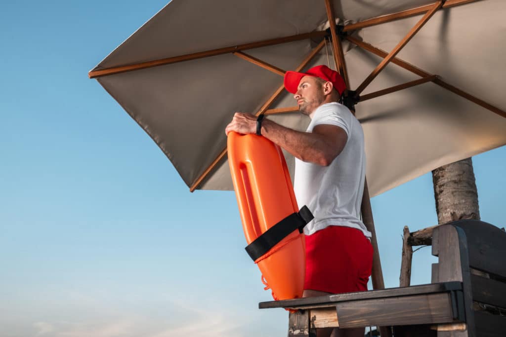 Portrait Of A Young Lifeguard With A Rescue Orange Buoy.