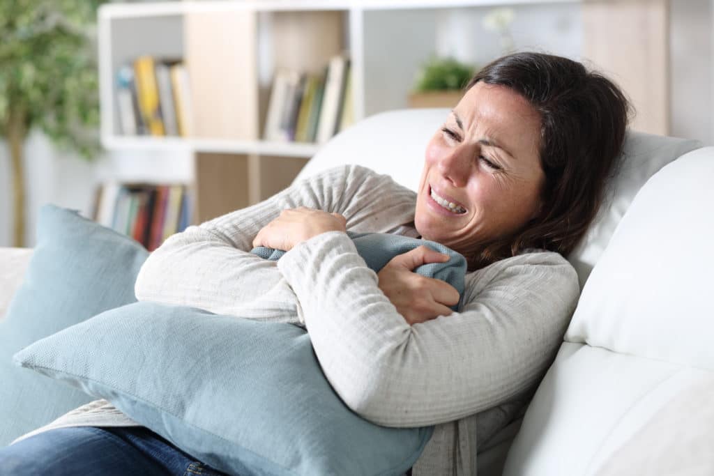 Sad Adult Woman Crying Sitting On The Sofa Holding Pillow