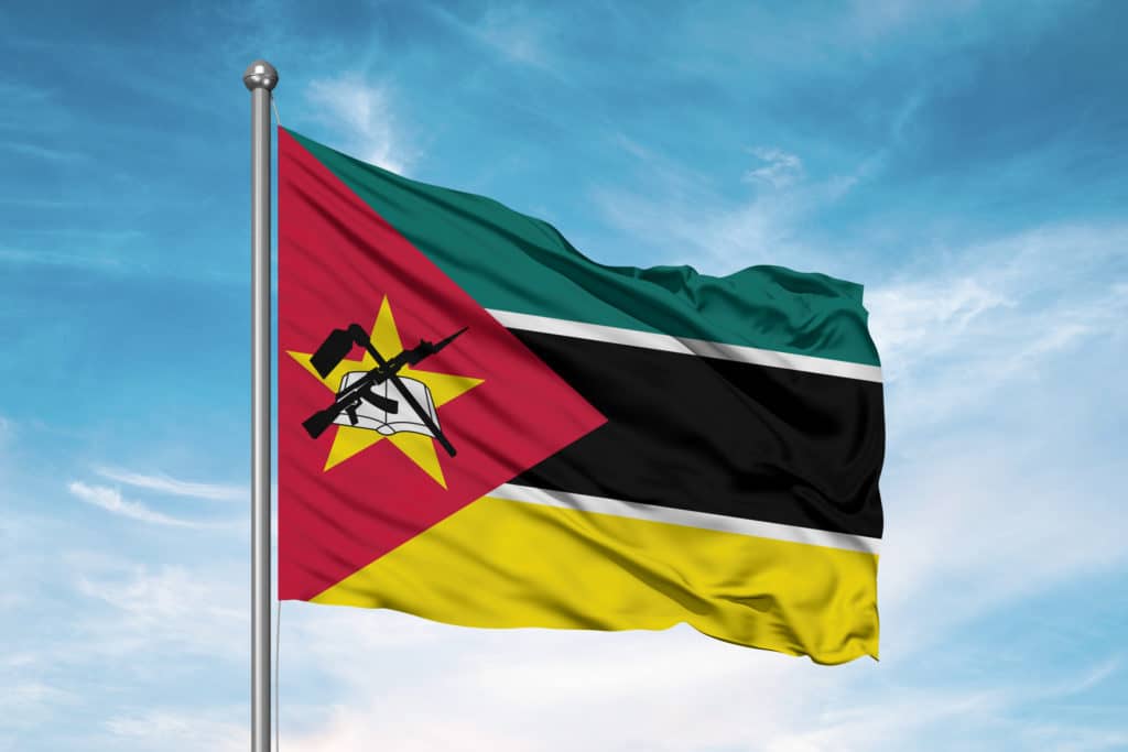 Mozambique National Flag Cloth Fabric Waving On Beautiful Sky.