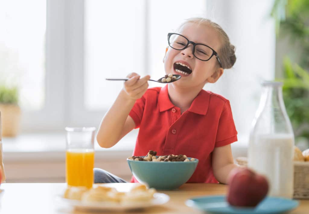 Happy Child Having Breakfast. Kid Eating Cereal In Kitchen.