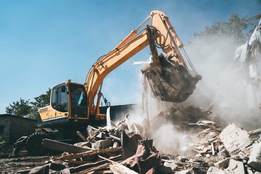 Destruction Of Old House By Excavator. Bucket Of Excavator Breaks
