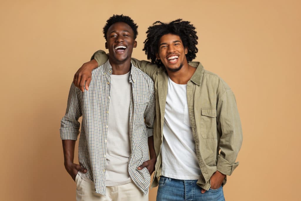 Portrait Of Two Happy Black Guys Embracing While Posing Over