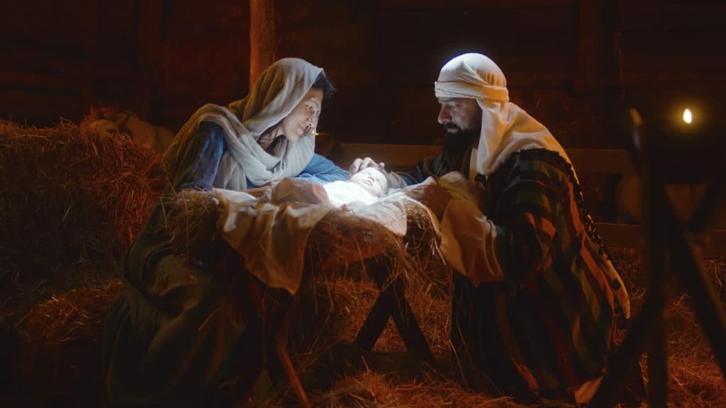 Mary And Joseph Caressing Baby Jesus In Illuminated Manger