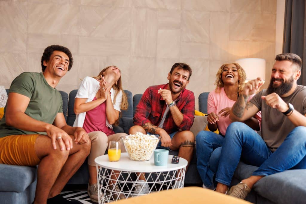 Group Of Friends Eating Popcorn And Laughing While Watching Funny