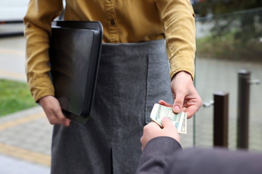 Client Giving Tips To Waitress In Outdoor Cafe Closeup